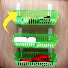 three green plastic baskets with toothbrushes and other bathroom items in them on a wooden wall