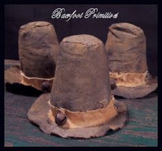 three brown hats with buttons on them sitting on top of a wooden table next to each other