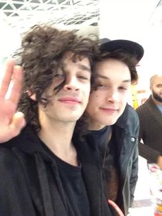 two young men with curly hair posing for the camera