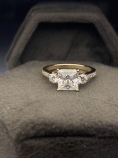 an engagement ring with three stones on it in a velvet box, showing the center stone