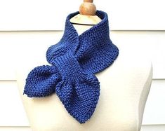 a blue knitted scarf sitting on top of a white mannequin