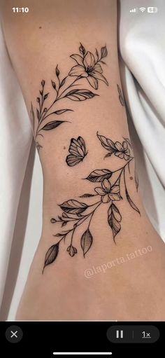 a woman's stomach with flowers and leaves tattooed on the side of her body