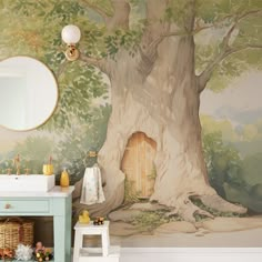 a bathroom with a tree painted on the wall next to a white sink and mirror