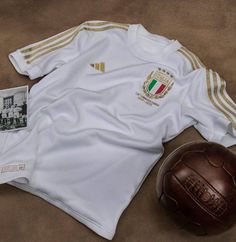 a soccer ball and jersey laying on the ground next to a brown leather football helmet