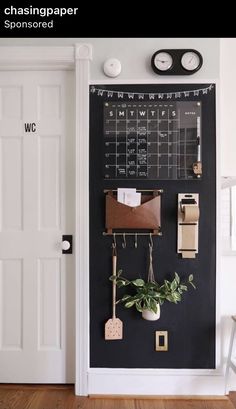 a chalkboard with magnets and plants on it in front of a white door