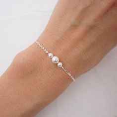 GENUINE STERLING SILVER - A GREAT KEEPSAKEThis dainty pearl bracelet is made using sterling silver chain and a sterling silver lobster clasp. Two 4mm Swarovski pearls are placed on either side of a 6mm center pearl (available in your choice of 5 colors). Comes in a gift box, perfect for gift giving. SIZING - IMPORTANT: To determine bracelet size, measure around your wrist and add 1/2 inch to get your bracelet size. Minimal Bracelet Silver, Small Silver Bracelets, Dainty Sterling Silver Pearl Bracelet, Sterling Silver Bracelets With Pearl Drop And Round Beads, Pearl Drop Sterling Silver Bracelet With Round Beads, Adjustable Sterling Silver Pearl Drop Bracelet, Adjustable Sterling Silver Pearl Charm Bracelet, Adjustable Sterling Silver Beaded Bracelets With Pearl Charm, Sterling Silver Beaded Bracelets With Pearl Charm