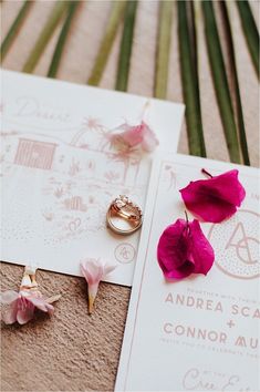 wedding rings and flowers on top of an envelope