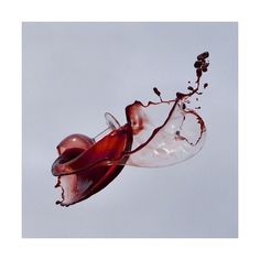 an upside down wine glass in the air with liquid pouring out of it and on its side