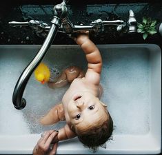 a baby in the sink playing with a ball