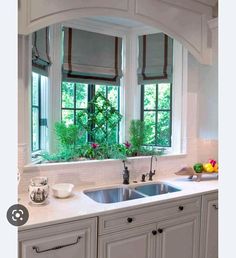 a kitchen with white cabinets and an arched window above the sink is decorated with flowers