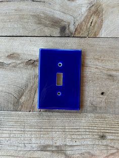 a blue light switch cover sitting on top of a wooden floor