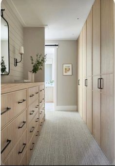 an empty hallway leading to a bedroom with large wooden cabinets and drawers on both sides