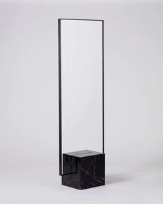 a tall black and white mirror sitting on top of a table