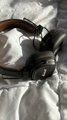 a pair of headphones laying on top of a white bed sheet covered in sheets