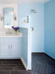 a bathroom with blue tiles on the walls and white cabinets, along with two sinks