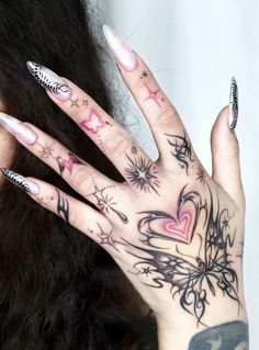 a woman's hand with tattoos on it and her nails in the shape of hearts