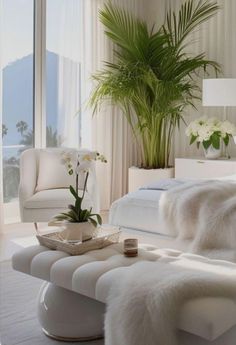 a bedroom with white furniture and large plants in the window, along with an ottoman