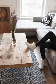 a woman sitting on a couch in front of a coffee table with her legs crossed