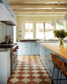 a kitchen with checkered tile flooring and wooden counter tops on both sides of the island