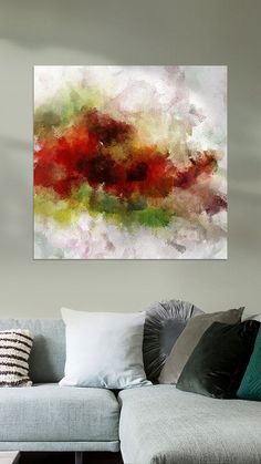 an abstract painting hangs above a couch in a living room with pillows on the floor