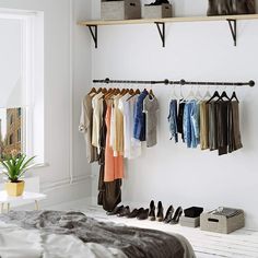 a bedroom with white walls and clothes hanging on the rack, shoes are lined up next to each other