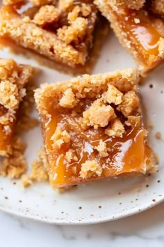 several pieces of dessert sitting on top of a white plate with crumb toppings