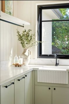 a kitchen with white cabinets and black windows