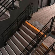 an overhead view of some stairs and railings in a building with wood floors, metal handrails and doors