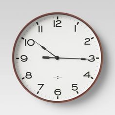 a white clock with black numbers on the face is shown in front of a gray background