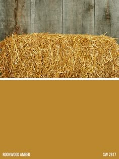 a wooden fence with hay in the foreground and an orange paint color swatch