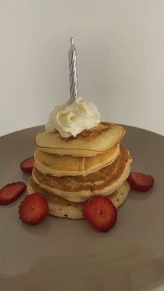 a stack of pancakes topped with whipped cream and strawberries