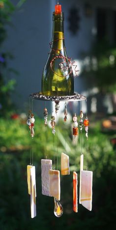 a wine bottle hanging from a wind chime with soap and honeycombs attached to it