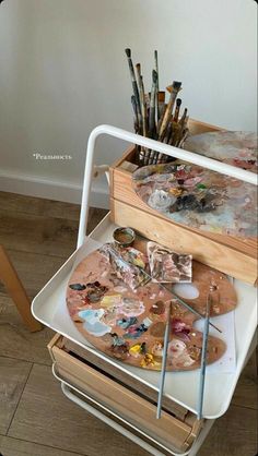 an artist's easel with paint, brushes and palettes sitting on it