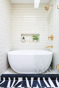 a white bath tub sitting in a bathroom next to a black and white tile floor