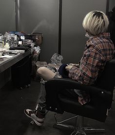 a person sitting in a chair with their feet on the desk while looking at his cell phone