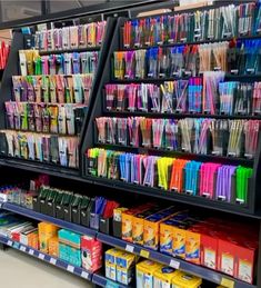 the shelves are filled with many different colored pens and pencils on display for sale