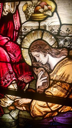 a stained glass window with the image of jesus holding a child in his lap and praying