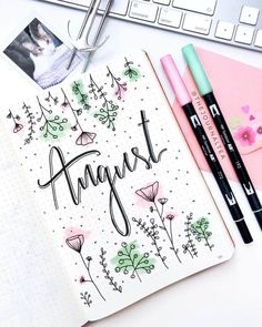 an open notebook with the word august written in cursive writing next to two markers