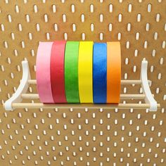 there are several rolls of colored tape on the rack