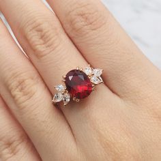 a woman's hand with a ring on it and a red stone in the middle