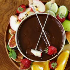 a bowl filled with chocolate and fruit on top of a wooden table