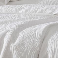 an unmade bed with white sheets and pillows