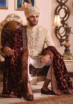 a man sitting on top of a chair wearing a white turban and red dress