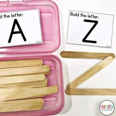 a pink plastic container filled with wooden clothes pins and letters to match the letter a - z