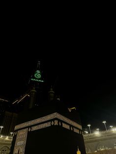 an illuminated clock tower in the middle of a city at night with lights on it's sides