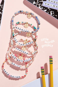 there is a book and pencils on the table next to some writing beads with words written in them