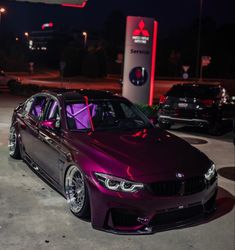 a purple car parked in front of a gas station at night with its hood up