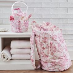 a pink flowered bag sitting on top of a white shelf next to folded towels