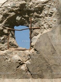 an old stone wall with a hole in the middle and a rusty iron bars sticking out of it