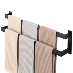 three towels hanging on a towel rack with black brackets and two beige and one white towels